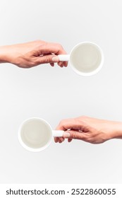 An empty white ceramic cups in a female hands on a white background, food mock-up, top view