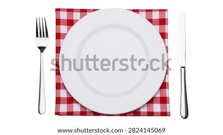 Empty white ceramic dinner plate with silver fork and knife on red checkered napkin
