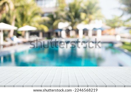 Empty white ceramic mosaic table  top and blurred swimming pool in tropical resort in summer banner background - can used for display or montage your products.