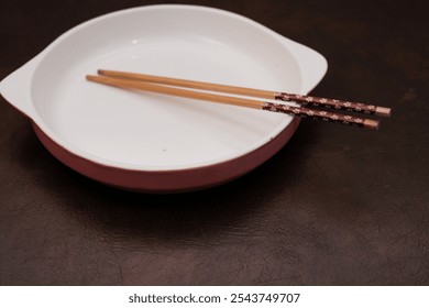 Empty white ceramic plate with  handle on the side and wooden chopsticks on the brown background, traditional wooden sticks for asian food. - Powered by Shutterstock