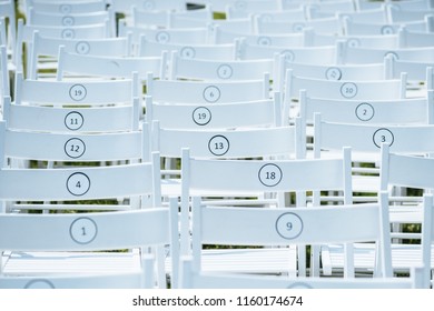 empty white chairs with numbers in rows outdoor