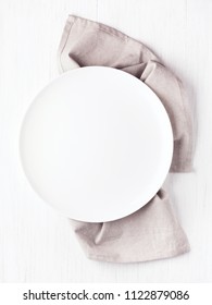 Empty White Circle Plate On Wooden Table With Linen Napkin. Overhead View, Mock Up.