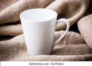 Empty white coffee cup on linen fabric.