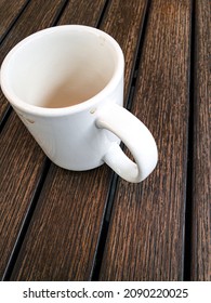 Empty White Coffee Mug On Wood Table, A Few Coffee Drop Stains On Mug. Detail And Texture Of Wood Grain. Quiet, Somber Mood. Shot From Slightly Above And At An Angle.