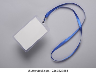 Empty white ID card badge mockup with blue belt on gray background. Staff identity name tag. Space for text and design. Top view. Flat lay