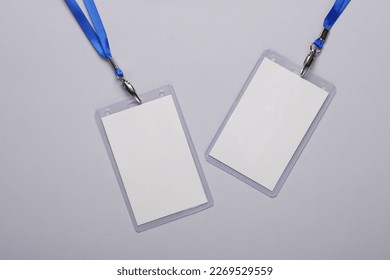 Empty white ID card badges mockup with blue belts on gray background. Staff identity name tags. Space for text and design. Top view. Flat lay