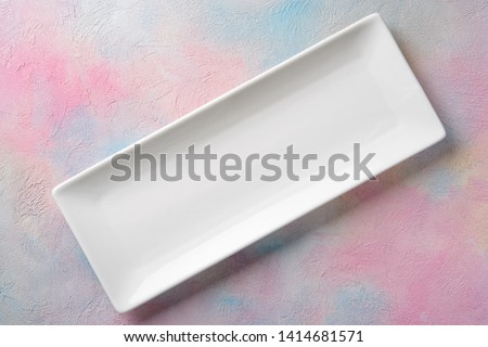 Empty white long rectangular plate on a colored background.