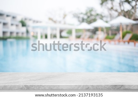 Empty white marble stone table top and blurred swimming pool in tropical resort in summer banner background - can used for display or montage your products.