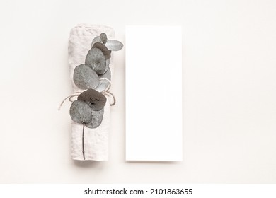 Empty White Menu Card Mockup With An Eucalyptus Branch And A Light Pink Napkin On A Minimal Neutral Background