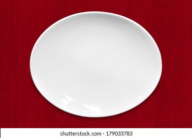 Empty White Oval Plate On Red Fabric.  Overhead View.