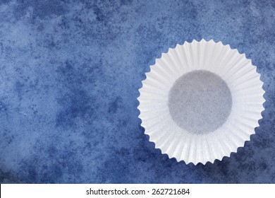 Empty White Paper Cupcake Case Over Textured Blue Background.  Overhead View.