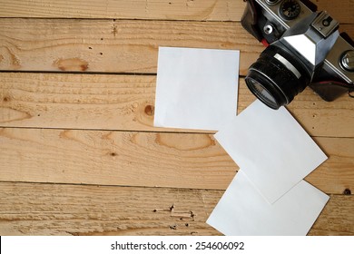 empty white paper note and old vintage camera on wooden table