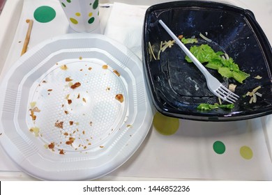 Empty White Plastic Plate And Black Bowl With Fork After Eating. Dirty Disposable Dishes On A Tray Top View. Fast Lunch At A Fast Food Cafe.