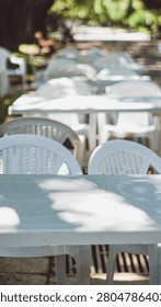 Empty white plastic tables and chairs in a park cafe