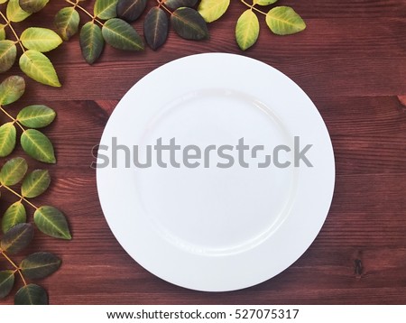 Empty white plat on the wooden brown background, top view