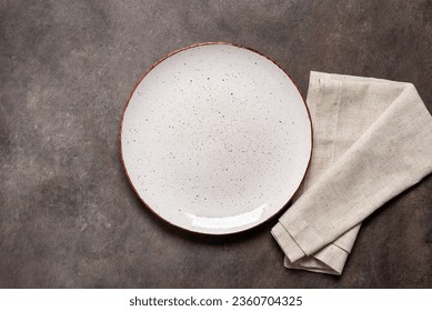 Empty white plate with a beige linen napkin on a brown rustic background. Top view, flat lay, copy space. - Powered by Shutterstock