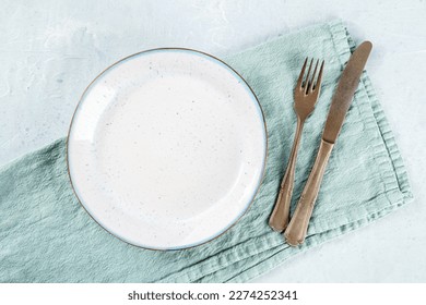 An empty white plate, with a fork and a knife, overhead flat lay shot on a slate background, the concept of dinner - Powered by Shutterstock