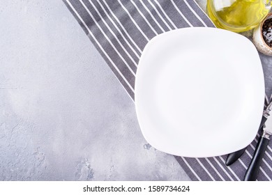 Empty white plate served with fork and knife. Top view. Copy space