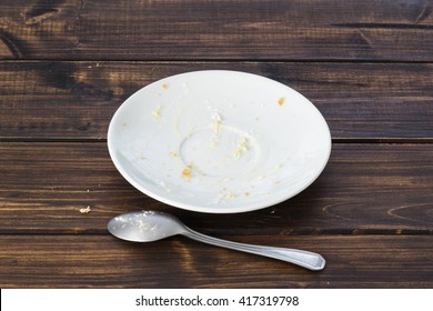 Empty White Plate And Spoon With Crumbs And Fat Stains After Vanilla Cream Cake Was Eaten