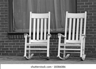 Empty White Rocking Chairs On City Street