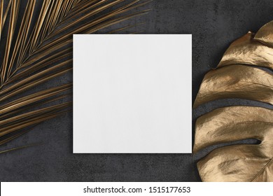 Empty White Square Poster Or Card Mockup With Golden Palm And Monstera Leaves On Abstract Dark Grey Textured Background. Tropical Elegant Trendy Dark Background. Flat Lay. Copy Space.