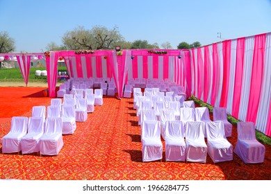 Empty White Velvet Chairs Arranged In Rows On Red Carpet In Indian Destination Wedding