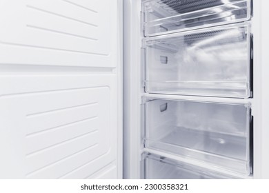 Empty white vertical new freezer with drawers.