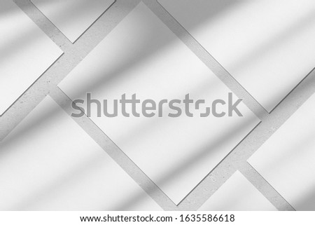 Empty white vertical rectangle poster or business card mockups with diagonal window shadow on the gray concrete wall.Flat lay, top view. For advertising, brand design, stationery presentation.