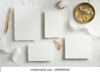 Empty White Wedding Stationery Mockups With Golden Rings, Pen, Ribbons On White Bed. Flat Lay, Top View. Wedding Invitations Template.