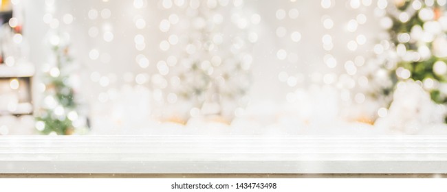 Empty white wold table top with abstract warm living room decor with christmas tree string light blur background with snow,Holiday backdrop,Mock up banner for display of advertise product - Powered by Shutterstock