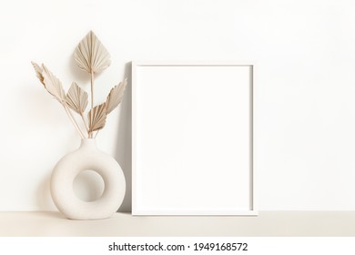 Empty White Wooden Picture Frame Mockup With A Modern And Minimal Round Vase And Dried Palm Leaves In Front Of A White Wall