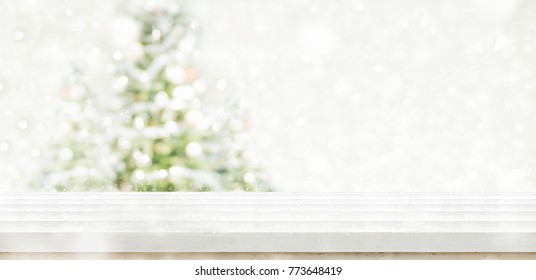 Empty White Wooden Table Top With Abstract Muted Blur Christmas Tree And Snow Fall Background With Bokeh Light,Holiday Backdrop,Mock Up Banner For Display Or Montage Of Product.