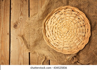 Empty Wicker Basket On Sackcloth On Wooden Table Background. View From Above