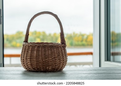 Empty Wicker Basket On A Window Sill Against Opened Window With Landscape View.