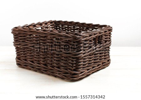 Empty wicker brown rattan basket on a white wooden background and white wall. Natural eco handmade item for home, interior. Home basket. 