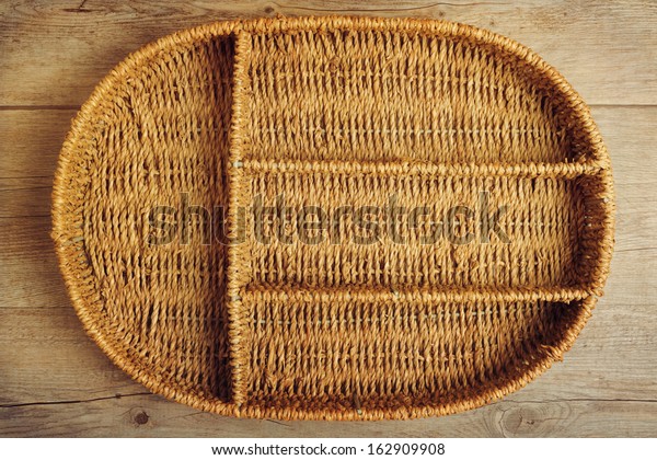Empty wicker tray\
box over wooden\
background