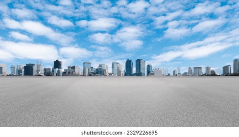 Empty wide asphalt road and city skyline. Side asphalt tarmac floor with buildings and modern cityscape, white clouds and blue sky background, highway for transportation, cloudy sky, high angle view
