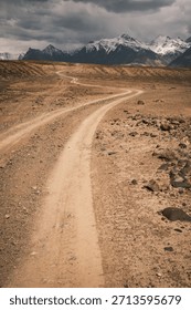 Empty winding road snaking through a remote and rugged wilderness. A powerful image of isolation and the vastness of the natural world, far from civilization
