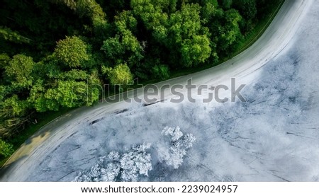 Empty winding road through dense forest in Sigulda, Latvia Winter and summer in one picture