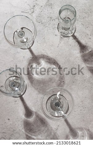 Empty wine glasses on grey background. Direct sunlight, aesthetic still life 
