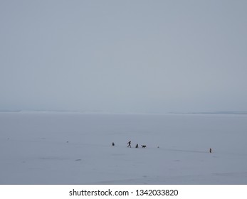 Empty winter landscape. Deep cloudy sky, snow and people on the frozen sea. Travelers in the Arctic