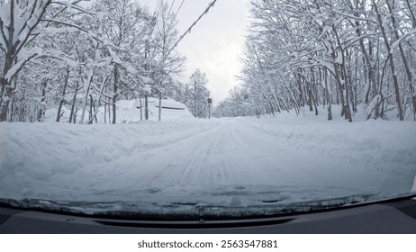 Empty winter road surrounded by snow covered trees and high snowdrifts. Challenging, yet picturesque car ride along a snowy winding highway in the embrace of snowy forest during a heavy snowfall.