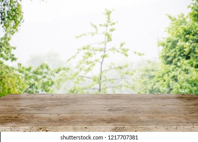 Empty Wood Brown And Blurry Abstract Background With Raindrop And Water Droplet On Window After Rain With Blurry Background Blurry  Green Trees And Field, Gray Clouds And Sky, Rainy Season In Country