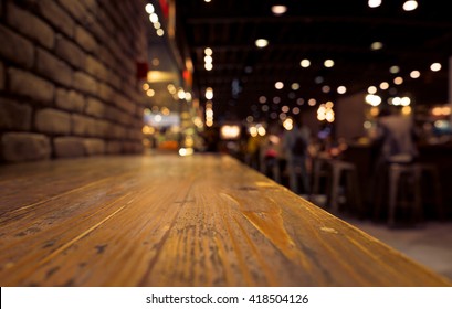 Empty Of Wood Counter Bar With Blur Cafe Restaurant In Dark Background/selective Focus .For Montage Product Display