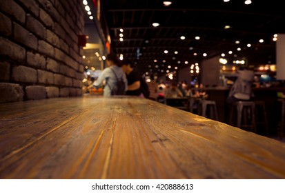 Empty Of Wood Counter Bar With Blur Cafe Restaurant In Dark Background/selective Focus .For Montage Product Display