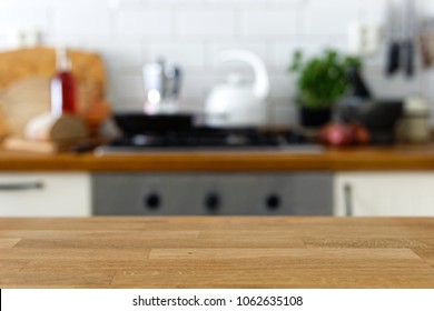 Empty wood counter in front of out of focus home kitchen background.