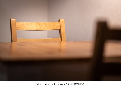 An Empty Wood Dining Table And Chair With Lighting Lamp Glowing, Lonely Abstract Feeling. Home Interior Furniture Object Photo, Selective Focus At The One Chair's Backrest Part.