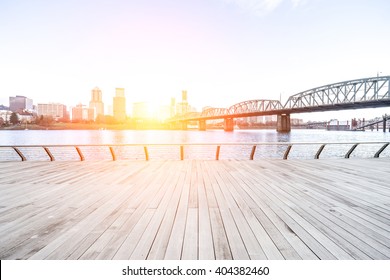 Empty Wood Floor Near Steel Bridge With Cityscape And Skyline Of Portland At Sunrise