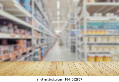 Empty wood table with blurred paint cans on shelves in large hardware store background. - Shutterstock ID 1844362987