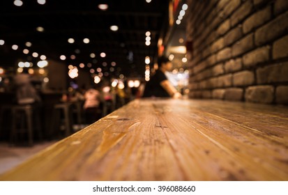 Empty Wood Table Top Of Bar With Blur Of Cafe Restaurant In Dark Night Background/selective Focus .For Montage Product Display